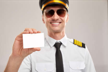 Smiling pilot showing blank business cardの写真素材