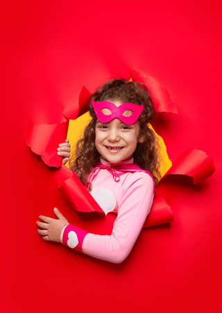 Cheerful superhero kid peeking out of paperの写真素材