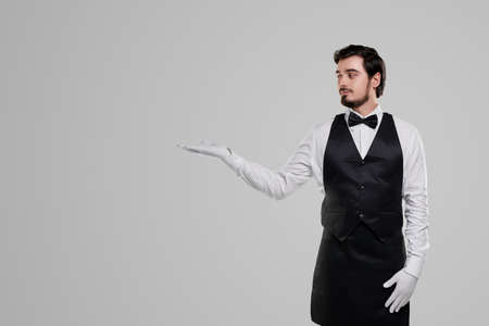 Elegant waiter pointing aside on blank spaceの写真素材