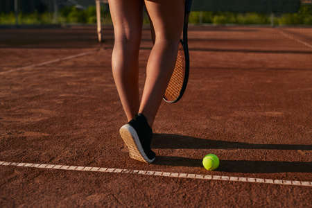 Crop female tennis player on sports courtの写真素材