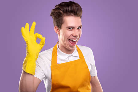 Happy cleaner showing OK gesture on purple backgroundの写真素材