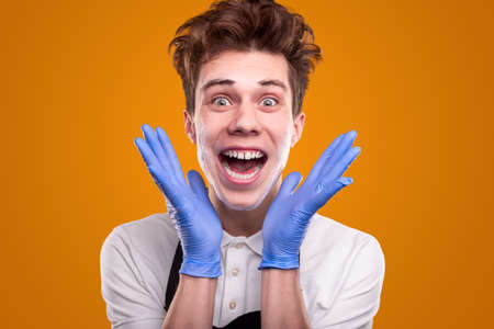 Excited male housekeeper in gloves look-in at cameraの写真素材