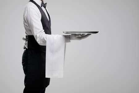 Elegant waiter in uniform carrying trayの写真素材