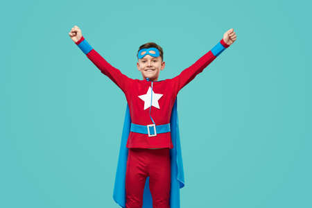 Cheerful superhero celebrating success with raised armsの写真素材