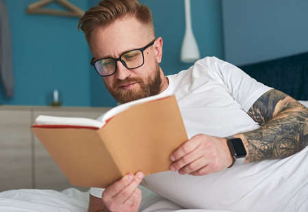 Man reading book on bed