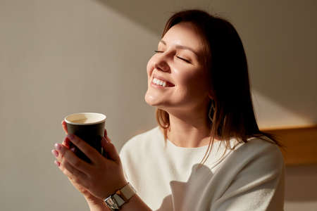Smiling woman enjoying morning coffeeの写真素材