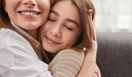Gentle woman cuddling daughter with closed eyesの写真素材
