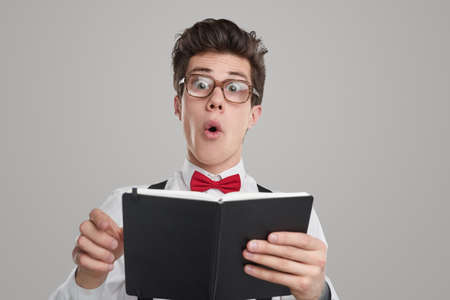 Smart geek in glasses reading bookの写真素材