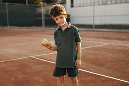 Boy with tennis balls on sports groundの写真素材