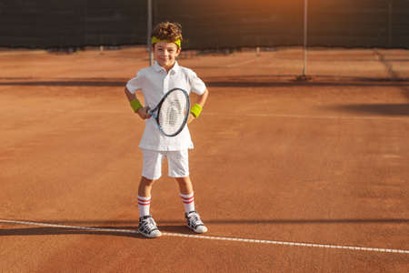 Boy with tennis racket on court in summerの写真素材