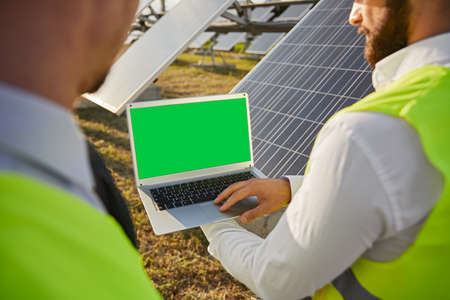 Engineers using laptop in field with solar panelsの写真素材