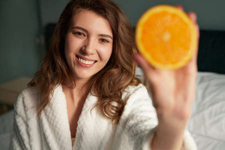 Woman showing orange at cameraの写真素材