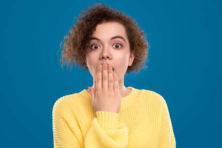 Shocked woman covering mouth in studioの写真素材