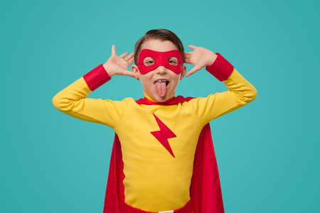 Funny boy in superhero costume making facesの写真素材