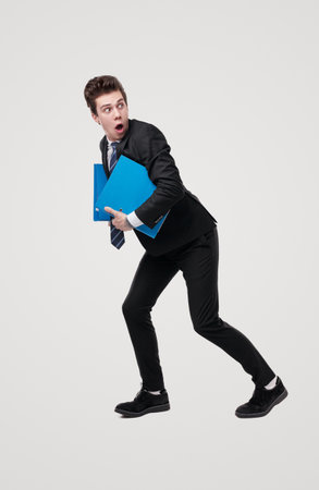 Silly shocked accountant running with documents in handsの写真素材