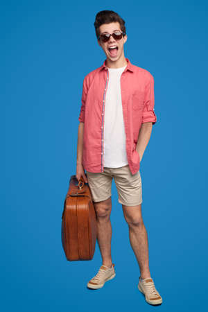 Cheerful traveler with suitcase in studioの写真素材