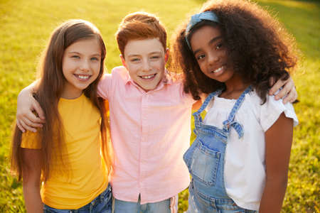 Company of diverse kids hugging in parkの写真素材