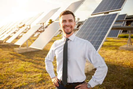 Cheerful businessman in field with solar batteriesの写真素材