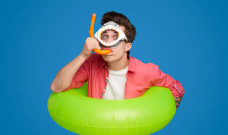 Funny man in swimming goggles and inflatable ring in studio