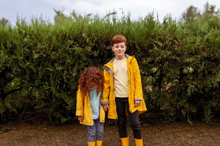 Redhead siblings in yellow raincoats in parkの写真素材