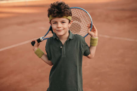 Smiling boy with tennis racket on courtの写真素材