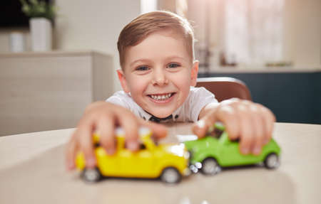 Cheerful boy playing with toy carsの写真素材