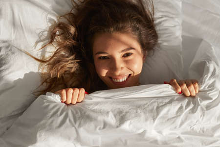 Lazy woman in bed in morningの写真素材