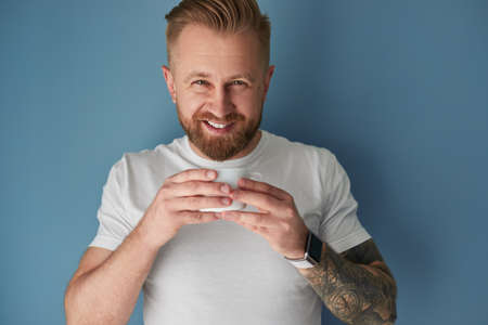 Smiling man drinking coffee in studioの写真素材