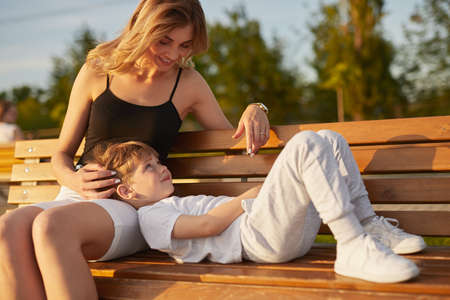 Mother caressing son on bench in parkの写真素材