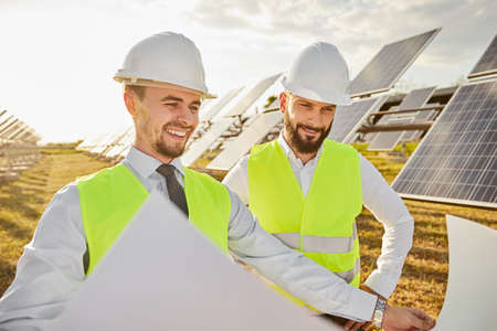 Male engineers examining draft in solar power station