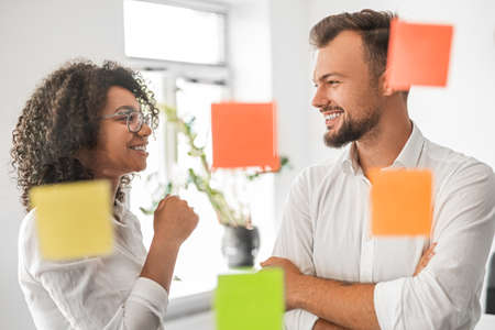 Happy diverse coworkers smiling during brainstorming in modern office
