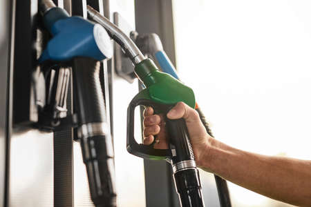 Crop man taking fuel pump nozzle at gas stationの写真素材