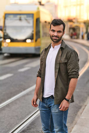Smiling ethnic guy standing on city street near tram stopの写真素材