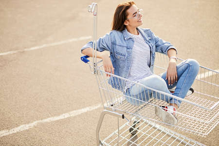 Relaxed female shopper sitting in trolleyの写真素材