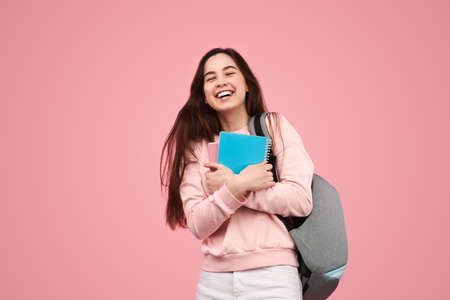Delighted young student with copybooks smiling after exams