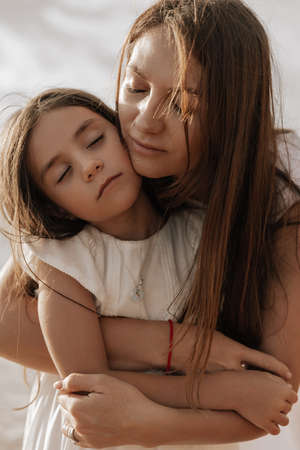Mother hugging daughter with closed eyes