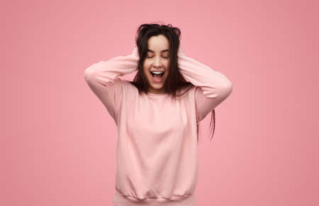 Delighted young lady yelling happily with closed eyes in studioの写真素材