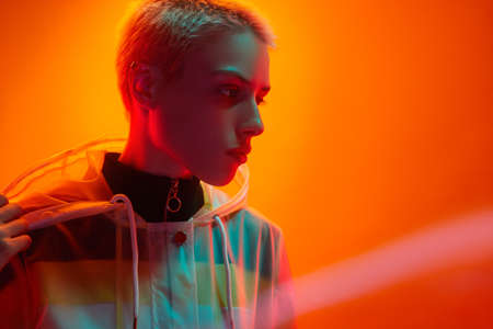 Young short haired woman looking away in bright neon studio