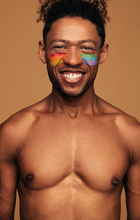 Cheerful black gay with colorful paint on faceの写真素材