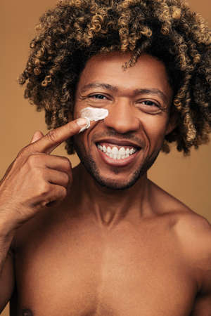 Happy black man smearing cream on faceの写真素材