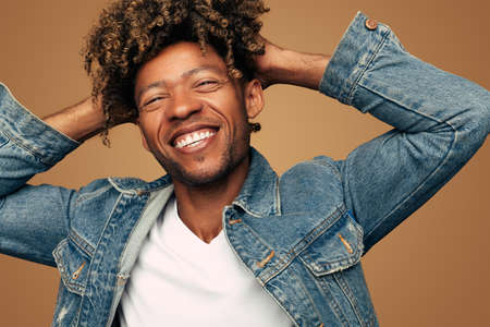 Merry black man touching curly hairの写真素材