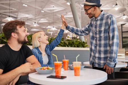 Friends greeting each other on meeting in cafeの写真素材