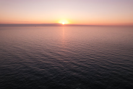 Sun setting over sea waterの写真素材