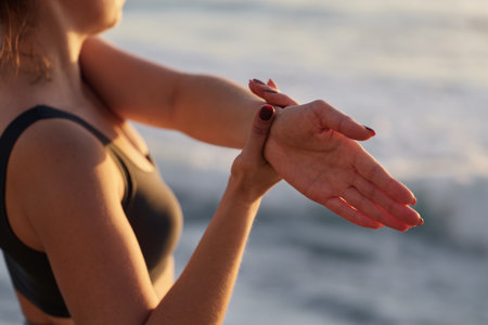 Crop sportswoman stretching arms during outdoor training on beachの写真素材