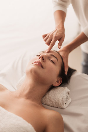 Acupuncturist pressing point on forehead of womanの写真素材