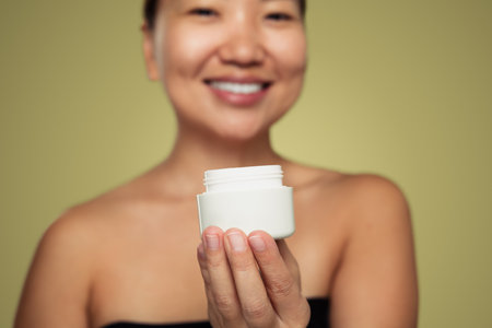 Crop ethnic model demonstrating cream jarの写真素材