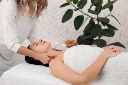 Crop therapist massaging neck of female client in SPA salonの写真素材
