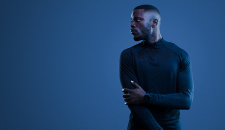 Unconfident black sportsman standing on blue backgroundの写真素材