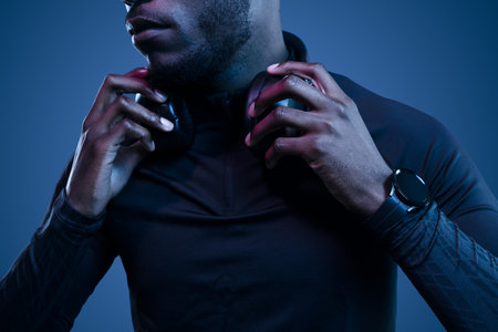 Crop black man adjusting headphones in gray studioの写真素材
