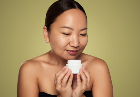 Asian woman smelling aromatic cream in jarの写真素材